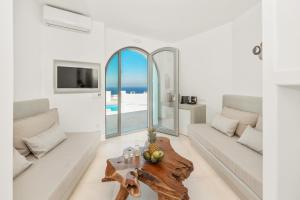 a living room with white furniture and a table at Oyster Luxury Suites in Imerovigli