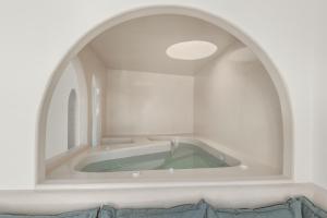 La salle de bains est pourvue d'une baignoire et d'une fenêtre cintrée. dans l'établissement Oyster Luxury Suites, à Imerovigli