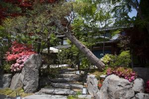 une maison avec des rochers et des fleurs devant elle dans l'établissement Kutsukake Stay Naka-Karuizawa, à Karuizawa