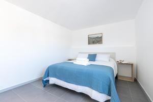 a white bedroom with a bed with a blue blanket at Apartaments Bellaire Cadaqués in Cadaqués
