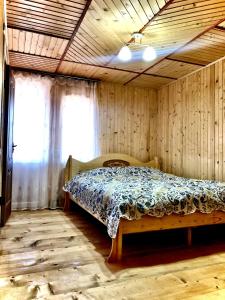een slaapkamer met een bed in een kamer met houten wanden bij Вілла Зозуля in Mykulychyn