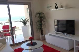 uma sala de estar com uma televisão de ecrã plano e plantas em Modern apartment with stunning sea view em Cala Millor