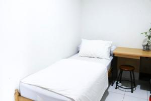 um quarto com uma cama branca e uma secretária em Rumah Kita em Padang