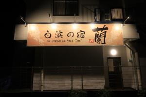 una señal en el lateral de un edificio por la noche en 白浜の宿　 蘭 en Shirahama