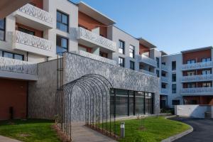 una entrada a un edificio con un arco de metal en DOMITYS LES NOTES FLORALES en Combs-la-Ville