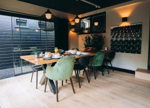a dining room with a wooden table and green chairs at B&B Bardot in Purmerend