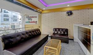 a living room with a leather couch and a tv at Itsy By Treebo - Palm Emirates in Bangalore