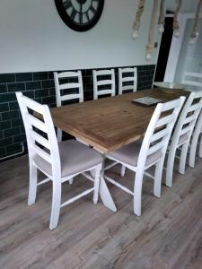 a wooden table with white chairs and a clock on the wall at Shore Lodge. 4 bed bungalow only mtrs from the beach. Sleeps 8 in Sutton on Sea