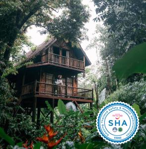 kobieta stojąca na balkonie domku na drzewie w obiekcie Our Jungle Camp - Eco Resort w Khao Sok