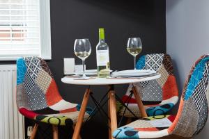 a table with two chairs and a bottle of wine at Delven House, Apartment 4 in Castle Donington
