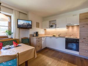 une cuisine avec des placards blancs, une table et une télévision dans l'établissement Appartement Lorenz, à St. Johann in Tirol