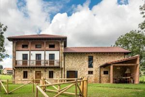 a large stone house with a wooden fence in front of it at Espectacular villa rural en Cabárceno in Penagos