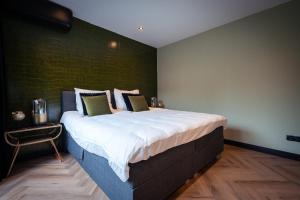 een groot bed in een kamer met een groene muur bij B&B Bardot in Purmerend