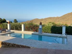 a swimming pool with a fence and mountains in the background at Casa Rural Mi Abuela Maria in Mojácar