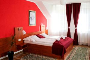 Un dormitorio con una pared roja y una cama. en Hotel Na Pekárně, en Sušice