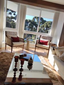 - un salon avec une table basse et des fenêtres dans l'établissement Serra Nevada Apartamento - Vista Catedral de Pedra, à Canela
