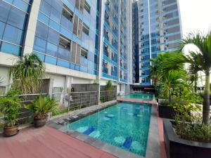 a swimming pool in front of a building at Cozy Tamansari Hive Cawang by Bonzela Property in Jakarta