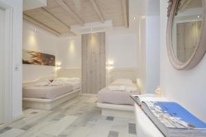 a bedroom with two beds and a mirror at Ostria Hotel in Agios Prokopios