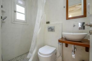 a white bathroom with a sink and a toilet at Ostria Hotel in Agios Prokopios