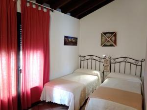 2 camas en una habitación con cortinas rojas en La Mina Rural Casas con encanto, en La Isabel