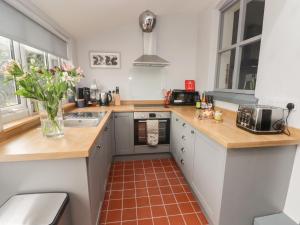 a kitchen with wooden countertops and a red tile floor at 6 Castle Street in Craven Arms