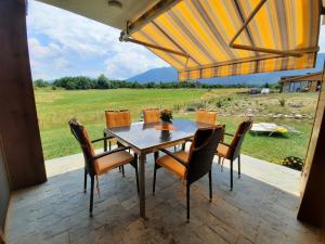 a table and chairs on a patio with a view of a field at Villa Serge in Pirin Hills in Razlog