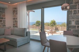 Sala de estar con mesa y sillas y vistas al océano en Acantha Villas, en Mókhlos