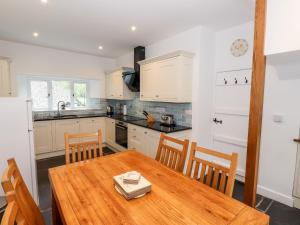 een keuken met een houten tafel en stoelen en een keuken met witte kasten bij Silverthwaite Cottage in Ambleside