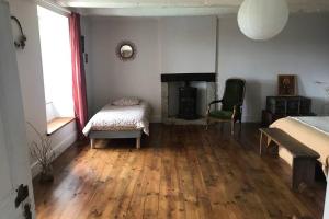 a bedroom with a fireplace and a bed and a chair at La Lande du Rest - Le Quillio Magnifique ancienne ferme de notables avec piscine chauffée in Le Quillio