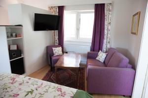 ein Schlafzimmer mit einem lila Sofa und 2 Stühlen in der Unterkunft Gasthof zum Goldenen Anker in Hainburg an der Donau