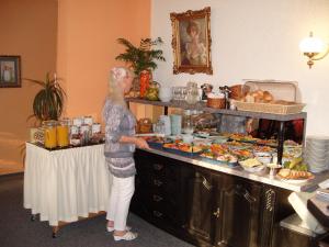 a woman standing in a kitchen preparing food at Hotel Haufe in Forst