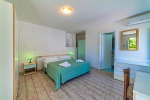 a bedroom with a green bed and a mirror at Albergo Le Querce in Ponza