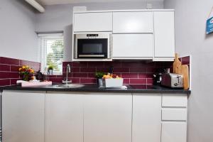 una cucina con armadi bianchi e lavandino di Delven House, Apartment 5 a Castle Donington