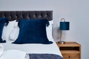 a bedroom with a bed with blue pillows and a lamp at Delven House, Apartment 5 in Castle Donington