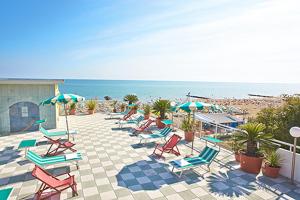 a group of chairs and umbrellas on the beach at Hotel Miramare in Caorle