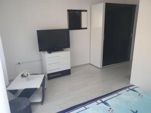 a living room with a flat screen tv and a table at Casa Simionov in Băile Herculane +9 photos
