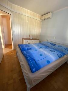 Ce lit se trouve dans un dortoir doté d'une couverture bleue. dans l'établissement Apartmán Perspekta 196, à Čatež ob Savi