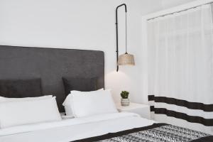 a bedroom with two white beds and a black and white headboard at Mr & Mrs White Mykonos in Platis Gialos