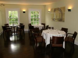 a dining room with white tables and chairs and windows at Flynns of Termonfeckin Boutique Hotel in Termonfeckin