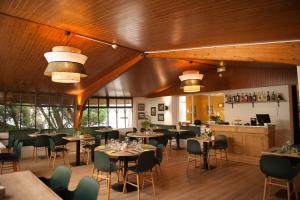 Logis Thermal في Saubusse: مطعم بسقوف خشبية وطاولات وكراسي