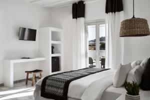 a white bedroom with a bed and a window at Mr & Mrs White Mykonos in Platis Gialos