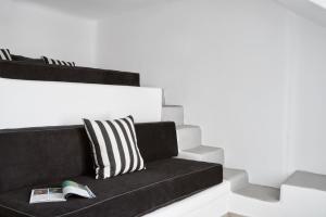 a black couch with a pillow and a book at Mr & Mrs White Mykonos in Platis Gialos