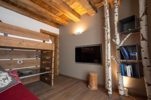 a bedroom with a loft bed with a tv and a tree at Casera Cornolera in Chies dʼAlpago