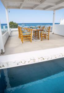 a patio with a table and chairs next to a swimming pool at Aegean Melody Suites in Vlychada
