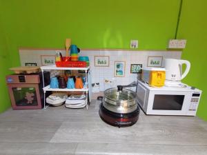 uma cozinha com um micro-ondas e um fogão com uma panela. em AV HomeStay - Kuching MJC em Kuching