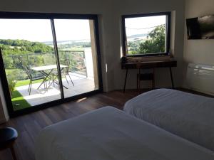 a bedroom with two beds and a balcony with a table at B&B CHEZ FOUCHS - Chambre d'hôtes in Dun-sur-Meuse