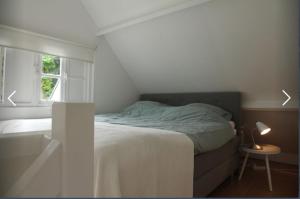 ein weißes Schlafzimmer mit einem Bett und einem Fenster in der Unterkunft Mary’s zomerhuis in Bergen