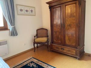 a room with a chair and a wooden cabinet at La Cour Zaepffel in Dambach-la-Ville