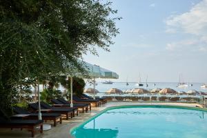 a swimming pool with lounge chairs and a view of the ocean at Parga Beach Resort in Parga