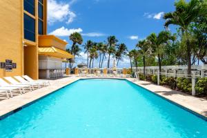 a swimming pool at a resort with chairs and palm trees at Wyndham Deerfield Beach Resort in Deerfield Beach